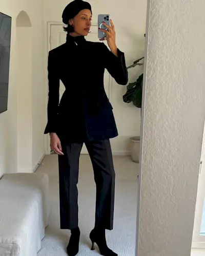 Fashion influencer Tylynn Nguyen wearing a black jacket, beret, trousers, and heeled boots.