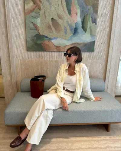 Fashion person Julie Ferrari wears a brown shoe outfit. She pairs her brown loafers with whit jeans, a white vest butter yellow shirt and bucket bag. This image was taken from her Instagram recently.