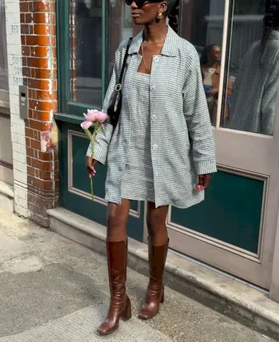 Fashion person Liv Madalline wears a brown shoe outfit. She pairs long from boots with a gingham jacket, matching dress and black shoulder bag. This image was taken from her Instagram recently.