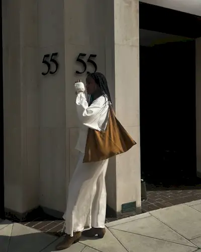 Shoes to wear with satin skirts: @iamnkirote wears a cream shirt and satin skirt with tan suede boots