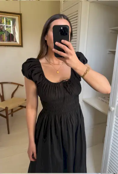 Woman wears black dress and brown sandals in mirror