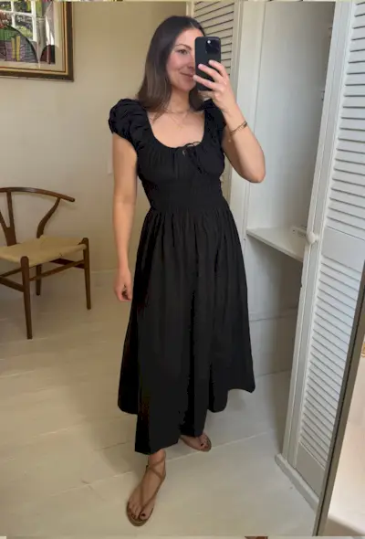 Woman wears black dress and brown sandals in mirror