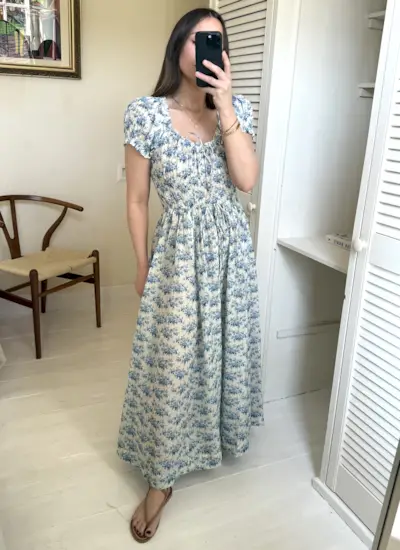 Woman wears floral blue maxi dress in mirror.