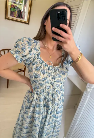 Woman wears floral blue maxi dress in mirror.