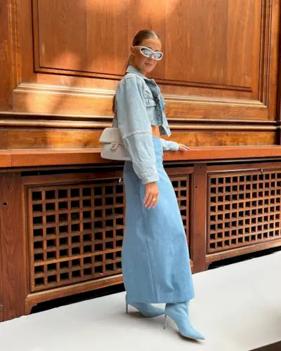 A woman wearing a long denim skirt with matching denim jacket and denim boots.