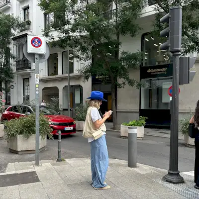 Woman wearing baggy white t-shirt, baggy striped pants, off-white bag, and bright blue cowboy hat.