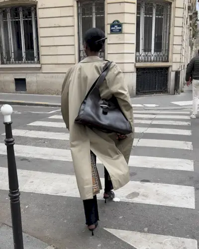 woman carrying a slouchy handbag and wearing a beige trench coat