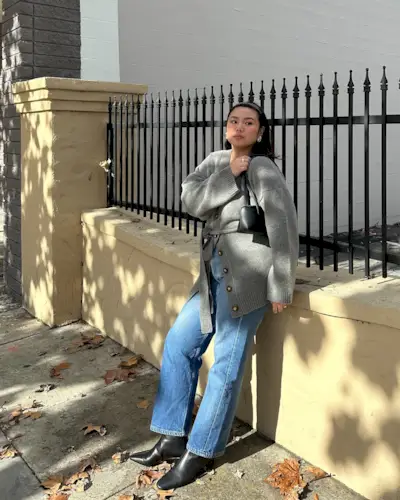 woman wears cosy grey knit, kick flare jeans and black ankle boot