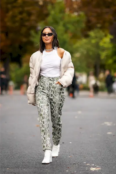 Woman wearing snake-print pants with a puffy coat and ankle boots.