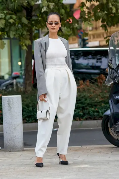 Woman wearing a cropped blazer with wide-leg white trousers.