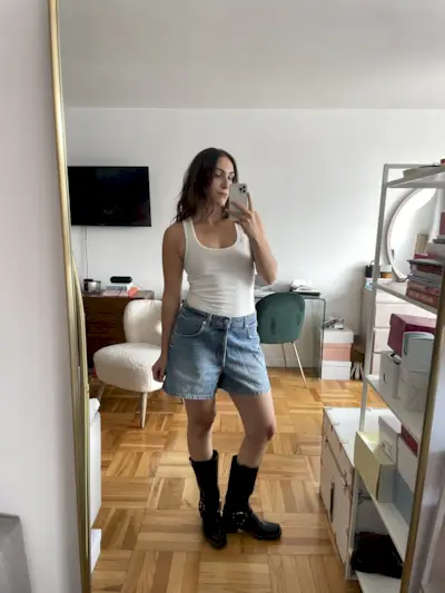 Anna LaPlaca wearing EB Denim Scout Shorts, black boots, and a white tank top.