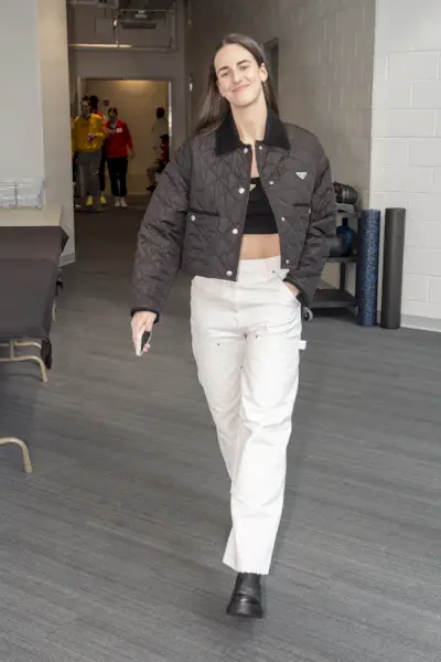 Caitlin Clark wore a PRADA white double satin shirt and skirt, embroidered rhinestone mesh top, black brushed leather slingback pumps, black Galleria handbag, and acetate sunglasses to the 2024 WNBA Draft in New York City on April 15th, 2024.