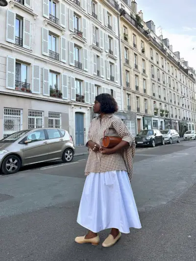 Franny in a white skirt and checkered blouse with loafers
