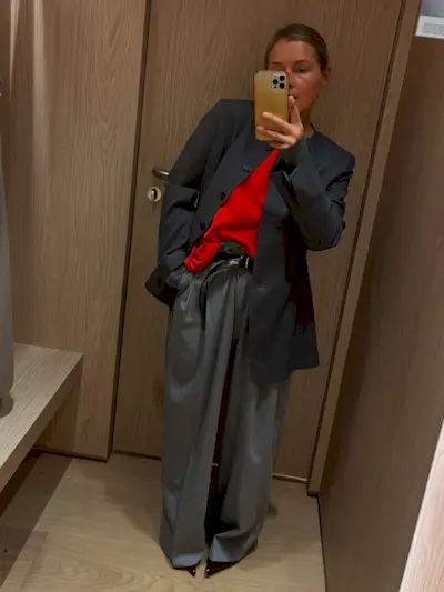 Anna in a blazer, trousers, and red t-shirt