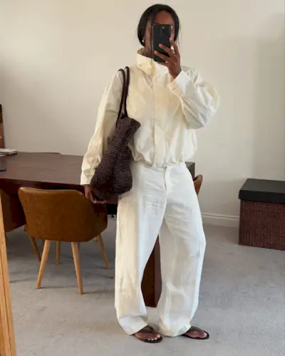 An image of @nlymarilyn wearing white linen trousers with a windbreaker, flip-flops and a woven leather bag, an example of what to wear instead of skinny jeans.