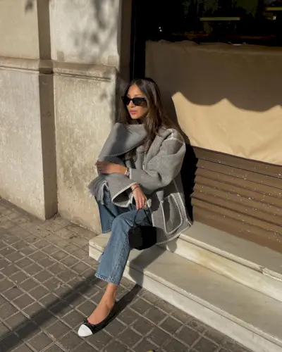 Woman sitting holding a The Row bag.