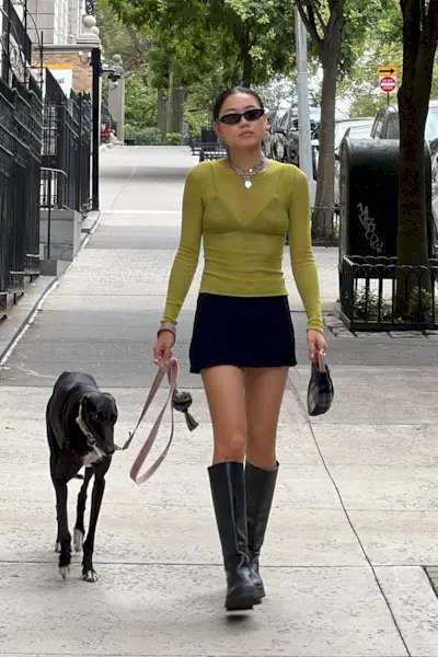 riding boot outfit shown in a photo of a woman in the street wearing a sheer green shirt with a black mini skirt and black riding boots