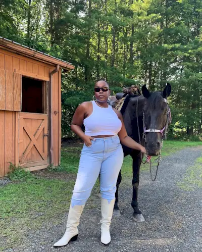 @aniyahmorinia wearing light blue skinny jeans, cowboy boots and a white racer tank top
