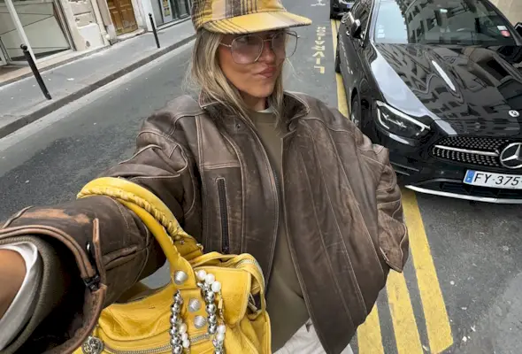 Sofia Coelho in a leather bomber jacket, yellow hat, and yellow Balenciaga purse.