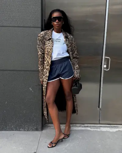 @nlmarilyn wears a white t-shirt with track shorts, kitten heels and a leopard print trench.