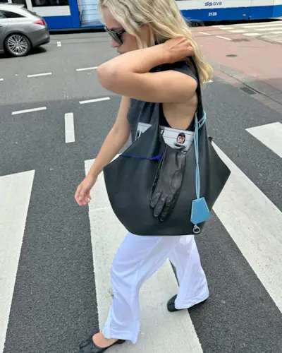 Stephanie Broek wearing a gray top, black bag, and flowy drawstring pants with ballet flats.