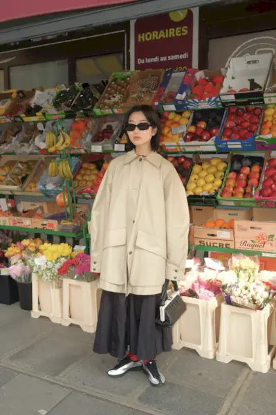 Vivid Wu standing next to a fruit and flower display.