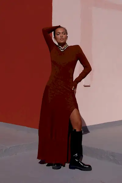a photo of a sweater dress outfit with a woman wearing a red maxi sweater dress with a black knee high riding boots and a chunky silver chain necklace