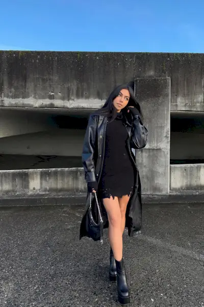 a photo of a sweater dress outfit with a woman wearing a black leather jacket over a black mini dress with black platform ankle boots with a black handbag