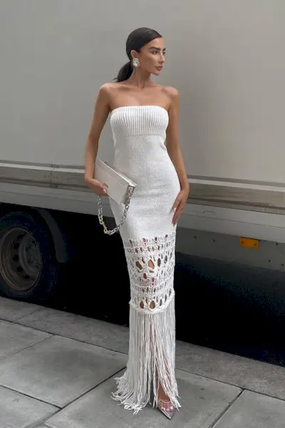 a photo of a sweater dress outfit with a woman wearing a strapless white knit dress with heels and a shoulder bag