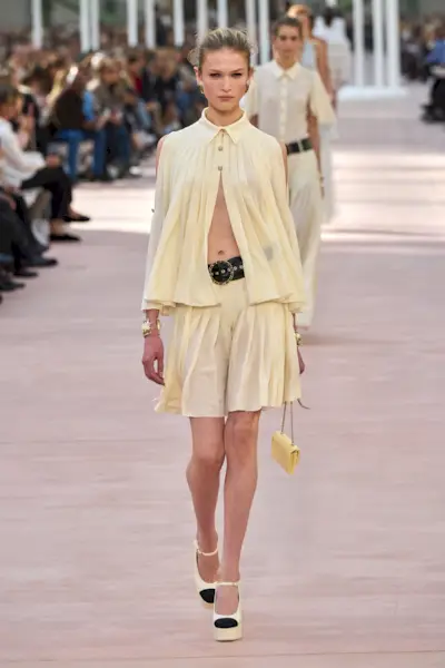 Chanel runway model wearing butter yellow dress, bags, and shoes.
