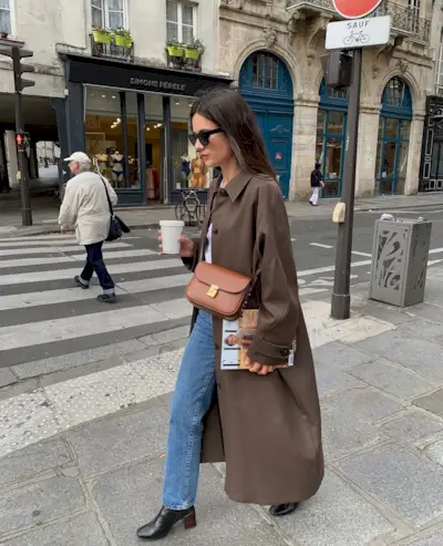 Leasy in a dark brown trench coat and leather bag