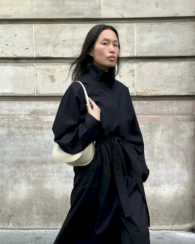 Viki in a black trench and white handbag
