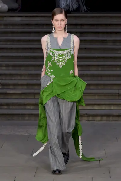 Woman in emerald green dress over gray pants on the spring 2025 Erdem runway.