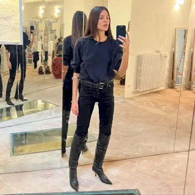 Woman wearing boots tucked into jeans trend fall 2025.