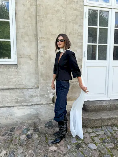 Woman wearing boots tucked into jeans trend fall 2025.