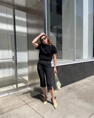 Anna wears a black tee, black capri pants, and beige muled heels.