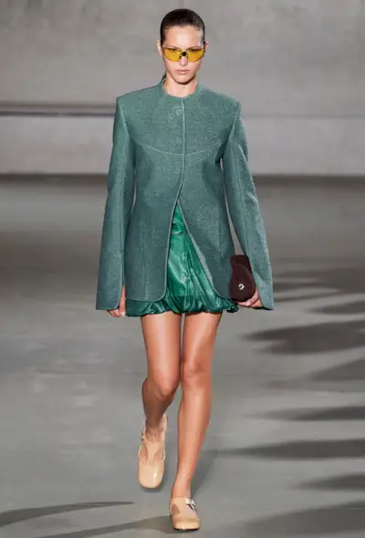 a model on the spring tory burch runway wearing a green ballon skirt with a tailored blazer and tan mary janes
