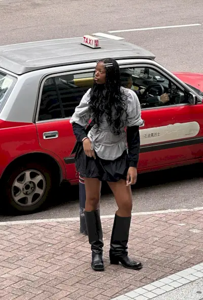 an influencer's outfit with a black mini bubble skirt styled with knee-high moto boots and a baggy gray t-shirt