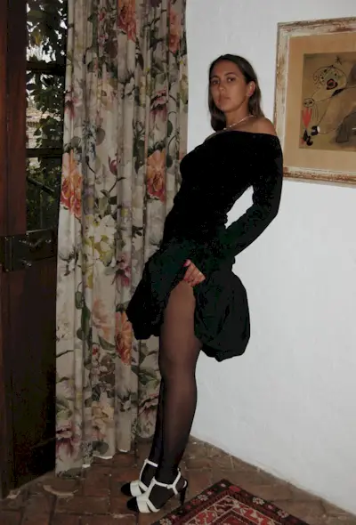 a woman wearing a black dress with a bubble skirt and tights and two-tone t-strap heels