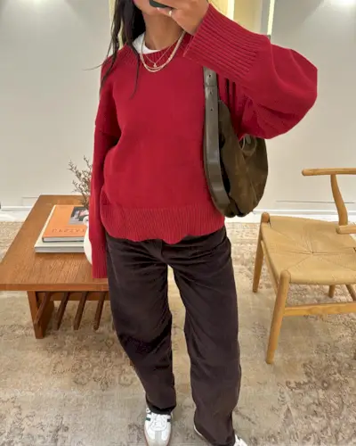 Woman wearing brown corduroy pants and a red crewneck sweater.