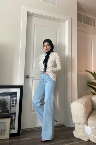 A woman wears a white blouse with light blue wide leg jeans