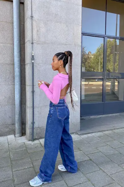 Amaka wears a pink long sleeve shirt, blue wide-leg jeans, and chunky white sneakers.
