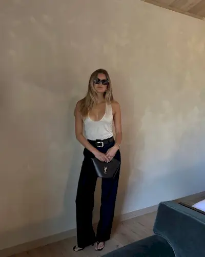 woman wearing trousers with white top and leather belt summer 2025