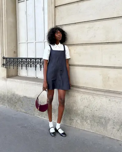 a photo of a woman wearing one of the best mary janes with a white polo layered under a denim mini dress