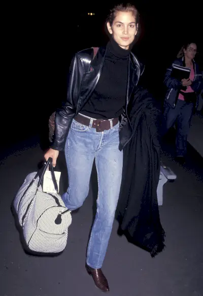 Cindy Crawford wears straight-leg jeans with an Alaïa leather jacket while travelling through the airport in 1991.
