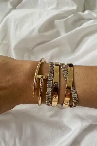 A woman's arm with multiple Cartier love bracelets.