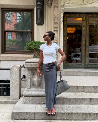 Influencer Deva wears a grey skirt, a white t-shirt and carried the grey The Row Magreux