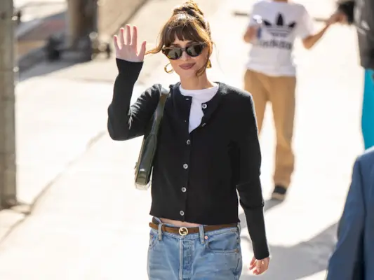 Dakota Johnson wears a black cardigan and straight-leg jeans