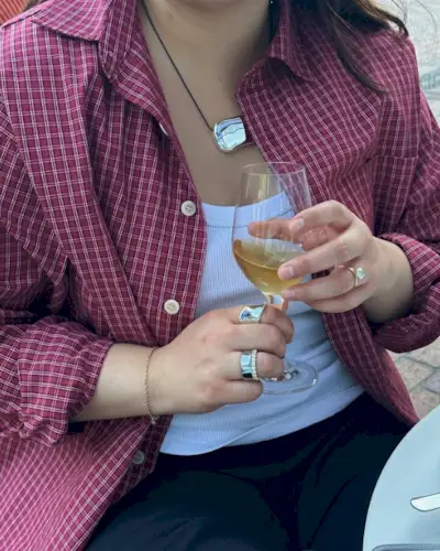 Marina wears a red plaid shirt, white tank top, black pants.