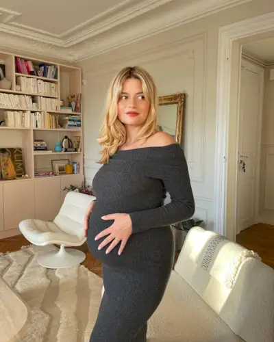 Sabina wears a gray off-the-shoulder maxi dress.